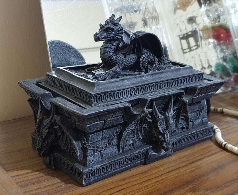 A black box shaped like a coffin. The lid has a dragon figure on top.