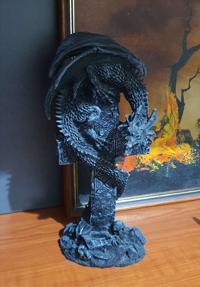 Black dragon statue. The dragon is curled around a christian cross.