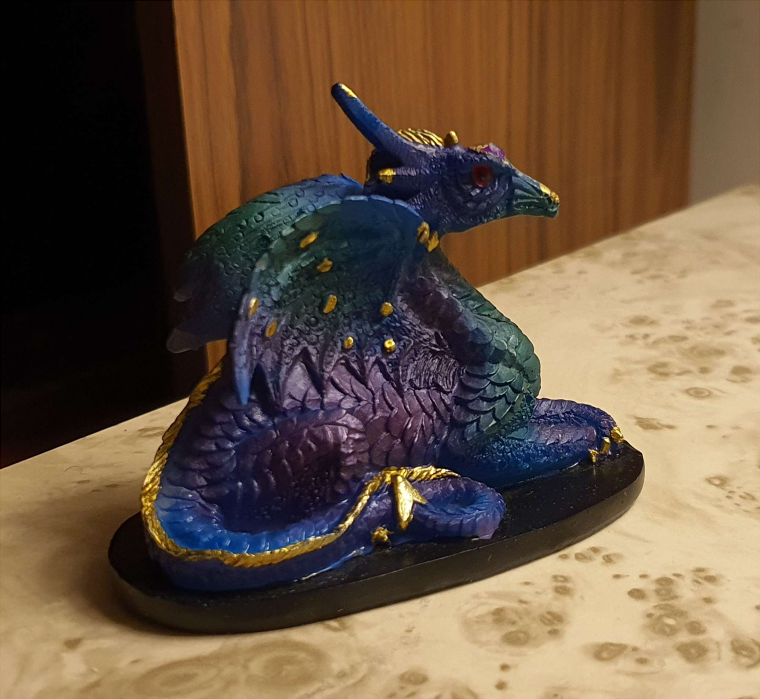 Small blue dragon statue. The dragon is lying down, with it's head up.
