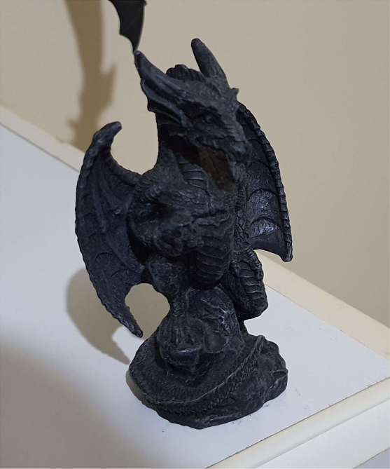 Small dragon statue. The dragon is black, and is sitting upright.